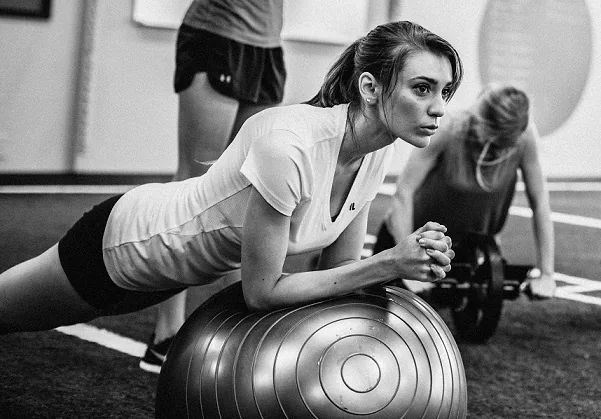 Focused member working through a stability-ball plank during a small-group session